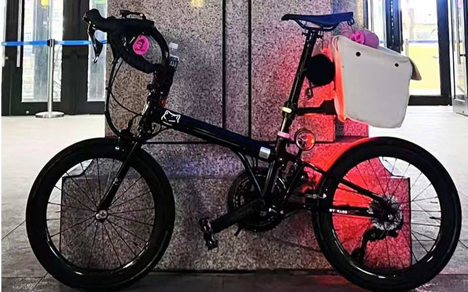 Black folding bike with a white rear bag on the seatpost