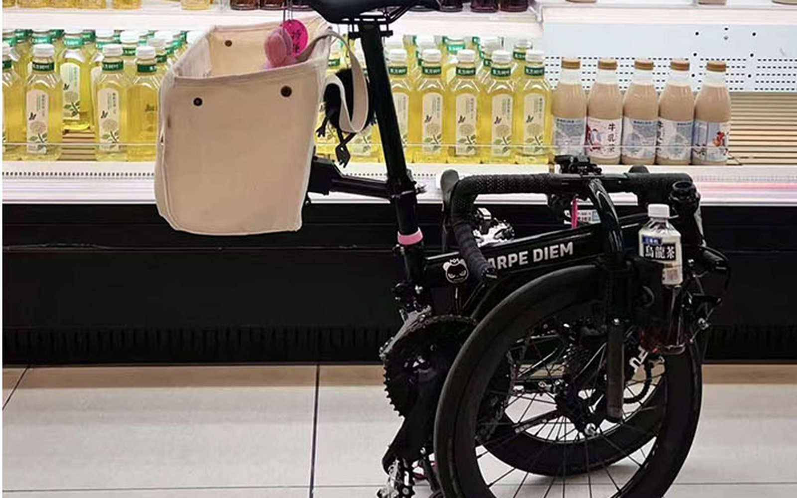Folded black bike with a canvas tote on the seatpost, indoors