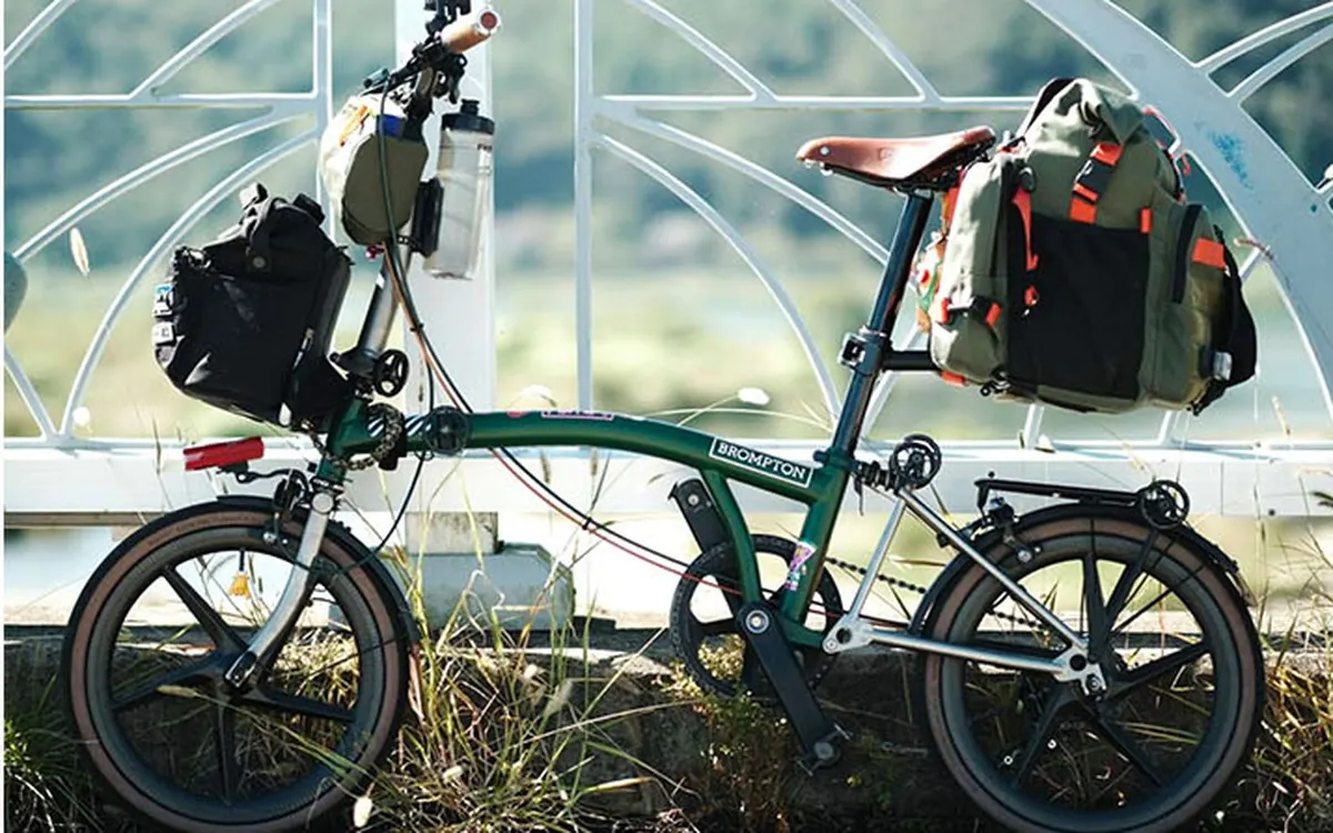 Green Brompton with an olive rear bag on the seatpost